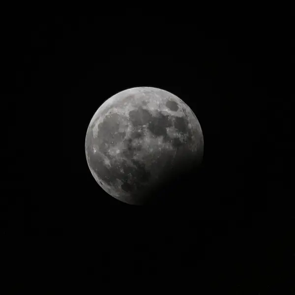 Full moon in the middle of the night with a partial lunar eclipse. Black background, copy space.