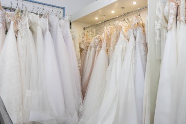 White and cream wedding dresses on a hanger in a bridal boutique. Close up.