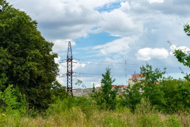 Şehrin dışında, yeşil ağaçların yanında yüksek voltajlı bir elektrik hattı var..
