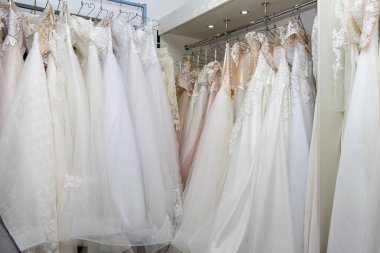 White and cream wedding dresses on a hanger in a bridal boutique. Close up.