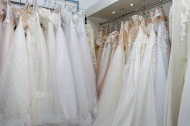 White and cream wedding dresses on a hanger in a bridal boutique. Close up.