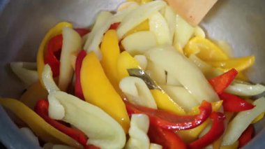Dişi aşçı büyük bir tatlı biber pişirir ve ahşap bir spatulayla karıştırır. Biberin yakın plan hazırlığı.
