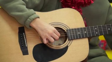 Bir genç akustik gitar çalar ve aniden çalmayı bırakır. Akustik gitar çalmayı öğrenmek ona eşlik eder. Canlı yakın çekim videosu.