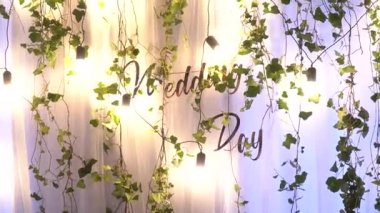 Düğün kemeri yapraklar ve fenerlerle süslenmiş. Düğün arkaplanındaki yazıt. Düğün günü.