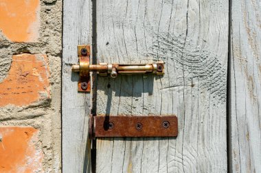 Old wooden door with a rusty metal lock on the background of a worn brick wall. clipart