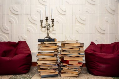 Kırmızı puf minderler arasında uzun bir kitap yığınının üzerinde klasik bir şamdan..