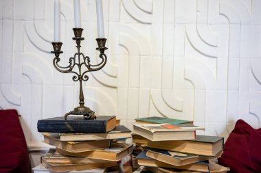 Örtülerin arasına gizlenmiş sırlar. Mumlar ve kitaplar entrika ortamı yaratır..