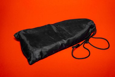 Parlak, siyah bir çanta canlı turuncu bir arkaplana yaslanır. Çeşitli depolama ihtiyaçları veya seyahat kolaylığı için işlevsellik ipuçları.