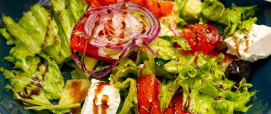 Renkli bir salatada çıtır yeşiller, kırmızı soğanlar, sulu domatesler ve üzerine sos serpiştirilmiş beyaz peynir bulunur. Bu sağlıklı yemek hafif bir öğle yemeği ya da yan yemek için mükemmel..