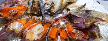 Geleneksel bir balık yemeği çeşitli parçaları dekoratif bir tabakta sergiler. Balık titizlikle hazırlanmış, parlak turuncu iç organları aşçılık sanatını ön plana çıkarıyor..