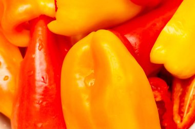 Güneşli bir yaz gününde pazarda sergilenen kırmızı ve sarı biberlerin canlı bir karışımı satışa hazır taze ürünler sergiliyor. Bu biberler yerel tarımı ve sağlıklı beslenmeyi ön plana çıkarıyor..