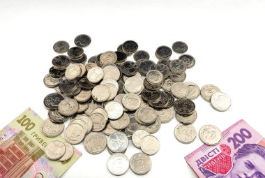 Çeşitli madeni paralar ve kağıt banknotlar beyaz bir yüzeye yayılır. Koleksiyonda, karmaşık tasarımlar ve para biriminin ayrıntılarını gösteren çoklu mezhepler yer alıyor. Ukrayna parası