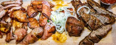 Pirzola ve sosis de dahil olmak üzere çeşitli ızgara etler bir tabakta düzenlenir. Taze soğan ve salsa yemeklere eşlik eder, canlı bir barbekü sergilenir. Açık hava toplantılarının tipik bir özelliği..