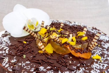 Güzel hazırlanmış bir çikolatalı pasta renkli meyveler, çikolata parçacıkları ve çikolata parçacıkları ile süslenmiş parlak bir krema içerir. Kutlama veya tatlı için mükemmeldir..