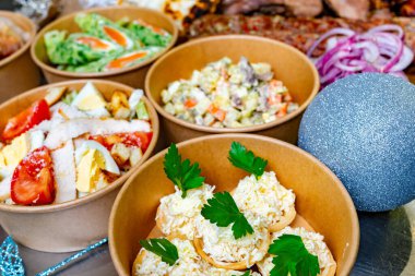 Canlı bir toplantıda çeşitli gıda maddelerinin renkli bir şekilde yayılması sergileniyor. Salatalar, kremalı soslar ve lezzetli ısırıklarla dolu kaseler misafirler için davetkar bir ortam yaratır..