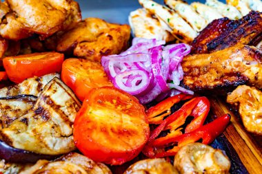 Canlı bir ızgara deniz ürünleri ve çeşitli sebzeler ahşap bir tabakta düzenlenir..