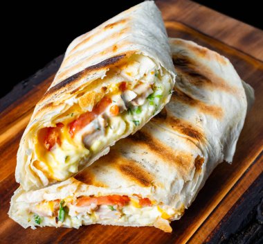 Sıcak ızgara ambalaj içi taze sebze ve lezzetli et karışımı ile doludur, ahşap bir tahtada sunulur, lezzetli katmanları ve çekici dokuları sergilenir..