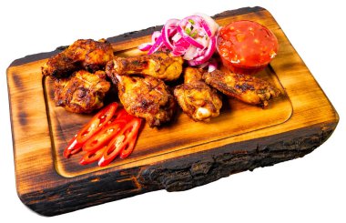 Dilimlenmiş jalapenolarla, kırmızı soğanlarla ve küçük bir kase domates sosuyla çevrili ızgara tavuk kanatları sergileniyor..