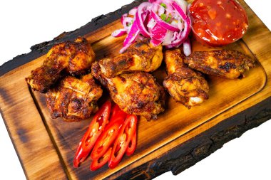 Izgara tavuk kanatları taze kırmızı soğanlar, dilimlenmiş biberler ve keskin sosla birlikte ahşap bir tabakta hazırlanır. Yaz mevsiminde toplanmaya hazırdırlar..