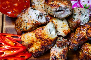 Yumuşak et parçaları, canlı kırmızı çan biberi dilimleri ve yanında bol soslu ahşap bir tabakta düzenlenir. Taze sebzeler renk ve çıtır çıtır ekler..