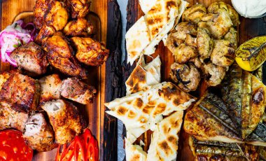 Lezzetli ızgara etler ahşap tabakta taze pişmiş ekmekle sergilenir. Domates ve soğan dilimleri lezzetli yayılıma canlı renkler ekler ve davetkar bir atmosfer yaratır..