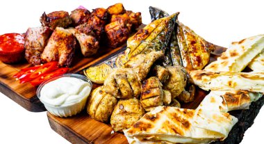 Tavuk ve balık da dahil olmak üzere çeşitli ızgara etlerin yanı sıra yassı ekmek, sos ve taze sebzelerin yer aldığı bir tabak. Bu renkli ziyafet akşam yemeği sırasında paylaşmak için mükemmel..