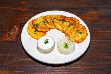 Yeşil otlarla süslenmiş bir tabak altın-kahverengi tuzlu krep iki küçük kase kremalı sosla birlikte gelir. Kırsal ahşap masa ortama sıcaklık katıyor..