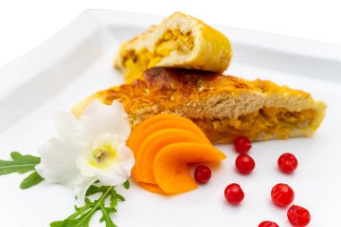 Taze yeşillikler, dilimlenmiş havuçlar ve dekoratif meyvelerle süslenmiş sebzelerle dolu lezzetli bir hamur işi, görsel cazibesini artırıyor..