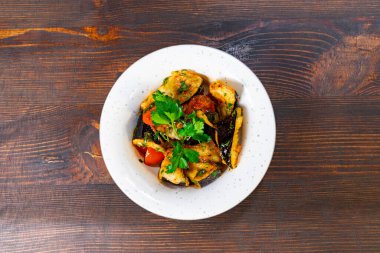 Lezzetli sebze yemekleri beyaz bir tabakta renkli sebzelerle düzenlenir. Yemek taze otlarla süslenir, iştah açıcı bir sunum yaratır..