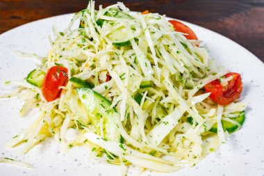 Paramparça lahana, olgun kiraz domatesleri ve otlarla süslenmiş salatalıklı canlı bir salata. Bu sağlıklı yemek hafif bir öğle yemeği ya da herhangi bir yemekte yemek için mükemmeldir..