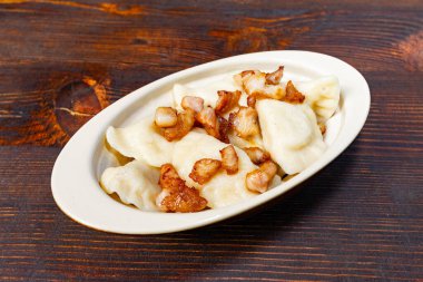 Bir tabak yumuşak hamur köftesi ve üstünde de kızarmış pastırma var. Bu doyurucu yemek için mükemmel. Geleneksel lezzet ve dokuları sergiliyor..