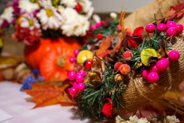 Parlak pembe böğürtlen ve kuru yapraklar bir sonbahar süsü oluşturur. Balkabağı sıcaklık katar. Arka plandaki çiçekler festival atmosferini güçlendirir. Mevsimsel toplantılar için mükemmeldir..