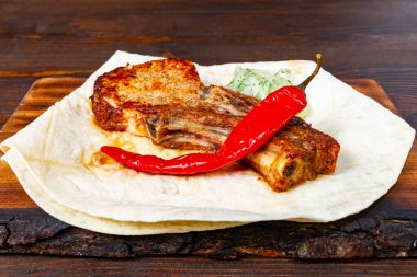 Izgara pirzola sıcak bir tortilla ve yanında taze kırmızı biber ile kaplıdır. Bu da her mutfak meraklısı için mükemmel bir ağız sulandırma tabağı yaratır..