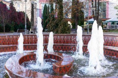 Şehir merkezinde berrak mavi bir gökyüzünün altında zarif bir tarihi bina duruyor. Sokak tabelaları ve tramvay hattı parlak bir günde canlı bir şehir atmosferi yaratır.