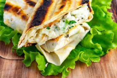 Lezzetli bir ızgara ekmek sargısında pirinç, otlar ve baharatlardan yapılmış kremalı bir dolgu bulunur. Canlı yeşil bir marul yatağında uzanır. İştah açıcı renkler ve dokular sergiler..