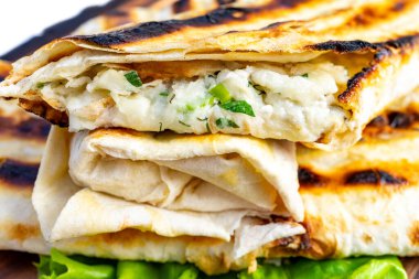 Krem peynirle ve taze otlarla kaplı lezzetli ızgara ekmek paketleri, yapraklı yeşilliklerin üzerinde servis edilir, güneşli bir günde mükemmel bir aperatif ya da hafif bir yemek olur..