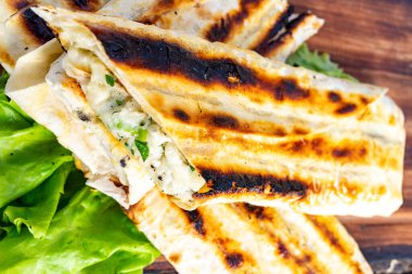 Lezzetli bir ızgara ekmek lezzetli bir dolguyla doldurulur. Tabak taze marul yatağında sunuluyor, iştah açıcı dokusunu ve rengini sergiliyor..