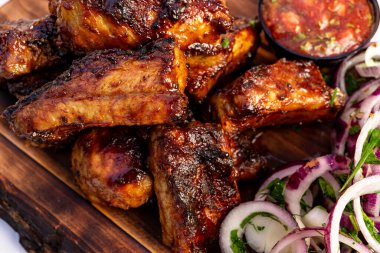 Yumuşak, lezzetli ızgara et parçaları ahşap bir tahtanın üzerinde bir kase salsa ve taze soğan ve otlarla birlikte mükemmel bir açık hava yemeği sergiliyor..