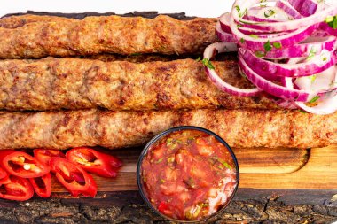 Bir tabak lezzetli ızgara kebap kırmızı soğan ve taze biberle süslenir. Zengin, baharatlı bir sos, canlı renkler ve aromalar sergiliyor..