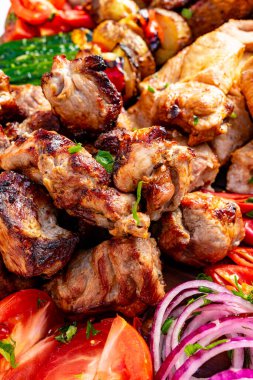 Lezzetli ızgara et kesikleriyle dolu canlı bir tabağa domates ve kırmızı soğan gibi taze sebzeler eşlik ediyor. Rengarenk düzenlemeler, toplantılar için mükemmel bir ziyafet sunuyor..