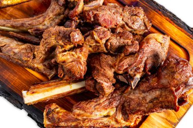 Sulu ızgara kuzu pirzolası ahşap bir tabakta oturur ve ağız sulandırıcı bir sunum sunar. Canlı yaz atmosferi bu lezzetli yemeğin tadını artırıyor..