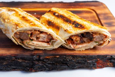 Taze ızgara bir ambalaj tahta bir kesme tahtasına oturmuş taze et ve canlı malzemeler ortaya çıkıyor. Altın sarısı tortilla bu tatmin edici yemeğe davetkar bir doku ekler..