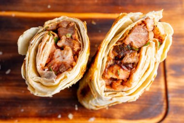 İki lezzetli ambalaj tabakası ızgara et, taze otlar ve ahşap bir tahtanın üzerinde baharatlar, zengin dokuları vurgulayarak ve malzemelerin iştah açıcı renklerini vurgulayarak.