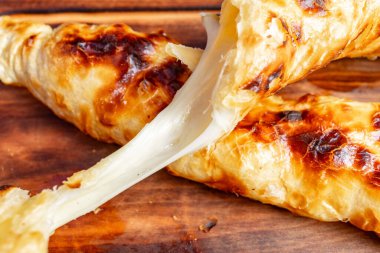 Erimiş peynirle dolu gevrek hamur işi ayrılır ve yapışkan içini ortaya çıkarır. Bu cezbedici ikram zengin dokular ve nefis bir atıştırmalık için mükemmel altın bir renk..