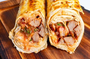 İki yeni hazırlanmış pakette leziz et, keskin soslar ve taze sebzeler sergileniyor. Altın kabuk, bu lezzetli yemeğin her bir lokmasının tadını çıkarmak için lokantaları davet eder..