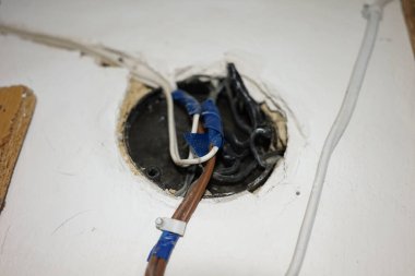 Exposed wiring is visible in a wall cavity as part of a home renovation project. The wires are secured with blue tape, indicating preparation for electrical updates. clipart