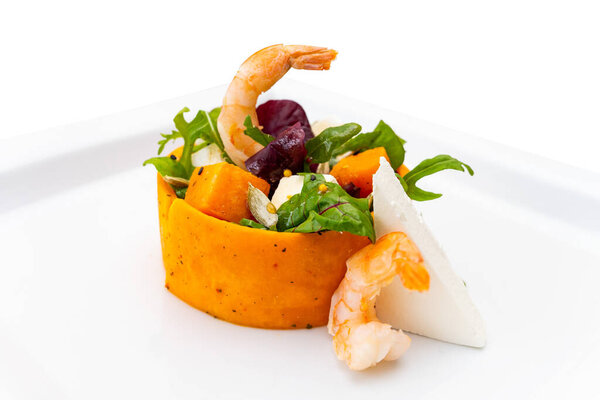 Vibrant shrimp salad features a blend of fresh greens, sweet pumpkin, and cheese, artfully arranged for an appealing presentation. Perfect for a light meal or appetizer.
