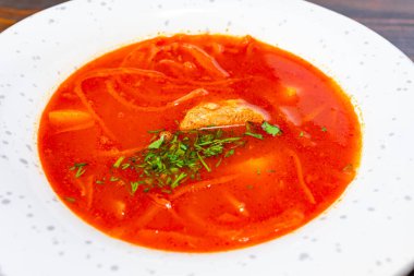 Canlı bir Ukrayna borsasında taze otlarla süslenmiş et parçaları ve ince dilimlenmiş sebzeler yer alır. Bu doyurucu yemek beyaz bir kasede servis edilir. Rahatlatıcı bir yemek için mükemmel.