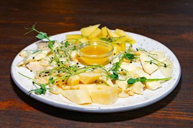 Çeşitli peynir çeşitleri yuvarlak bir tabakta güzelce düzenlenmiştir. Bal eşliğinde ve taze otlarla süslenmiş bu yemek, toplantılar sırasında paylaşmak için mükemmeldir..