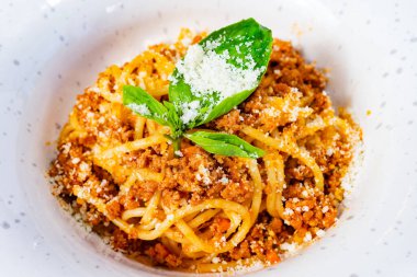 Baştan çıkarıcı bir makarna tabağı taze otlar ve rendelenmiş peynirle dolu bir kasede sunulur. Yemek iştah açıcı görünüyor, zevki davet eden zengin lezzetleri ve dokuları vurguluyor..